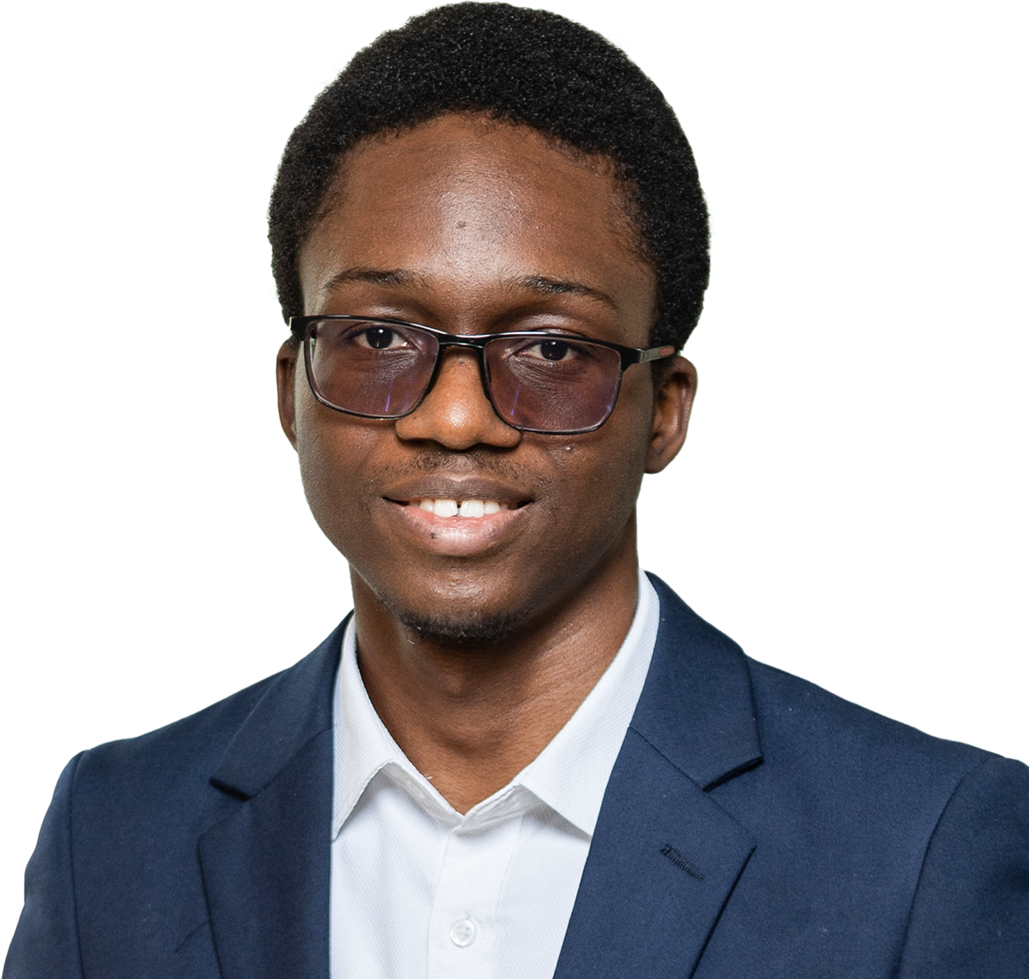 Smiling young man with short curly hair and glasses wearing a navy blazer and white shirt.