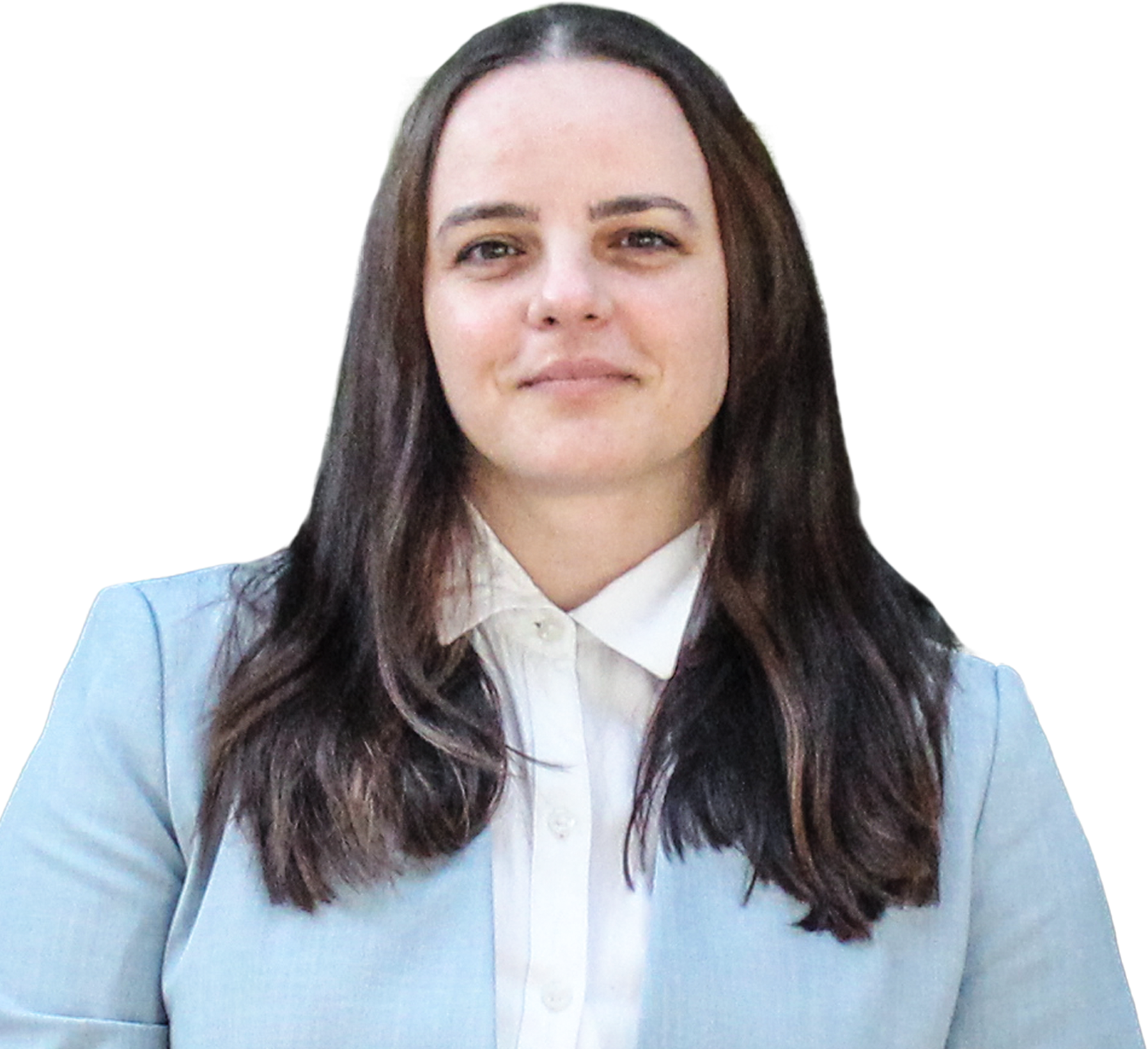Woman with long dark hair wearing a light blue blazer and white button-up shirt, standing in front of green plants.