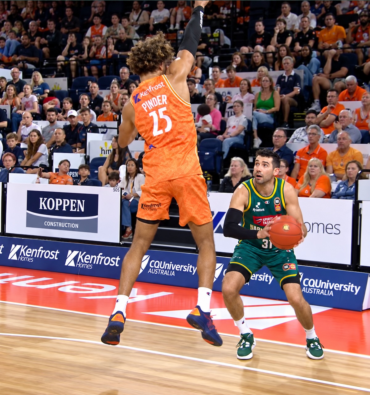 Cairns Taipans big man Keanu Pinder jumps to challenge Dakota Mathias' three point shot from the left corner
