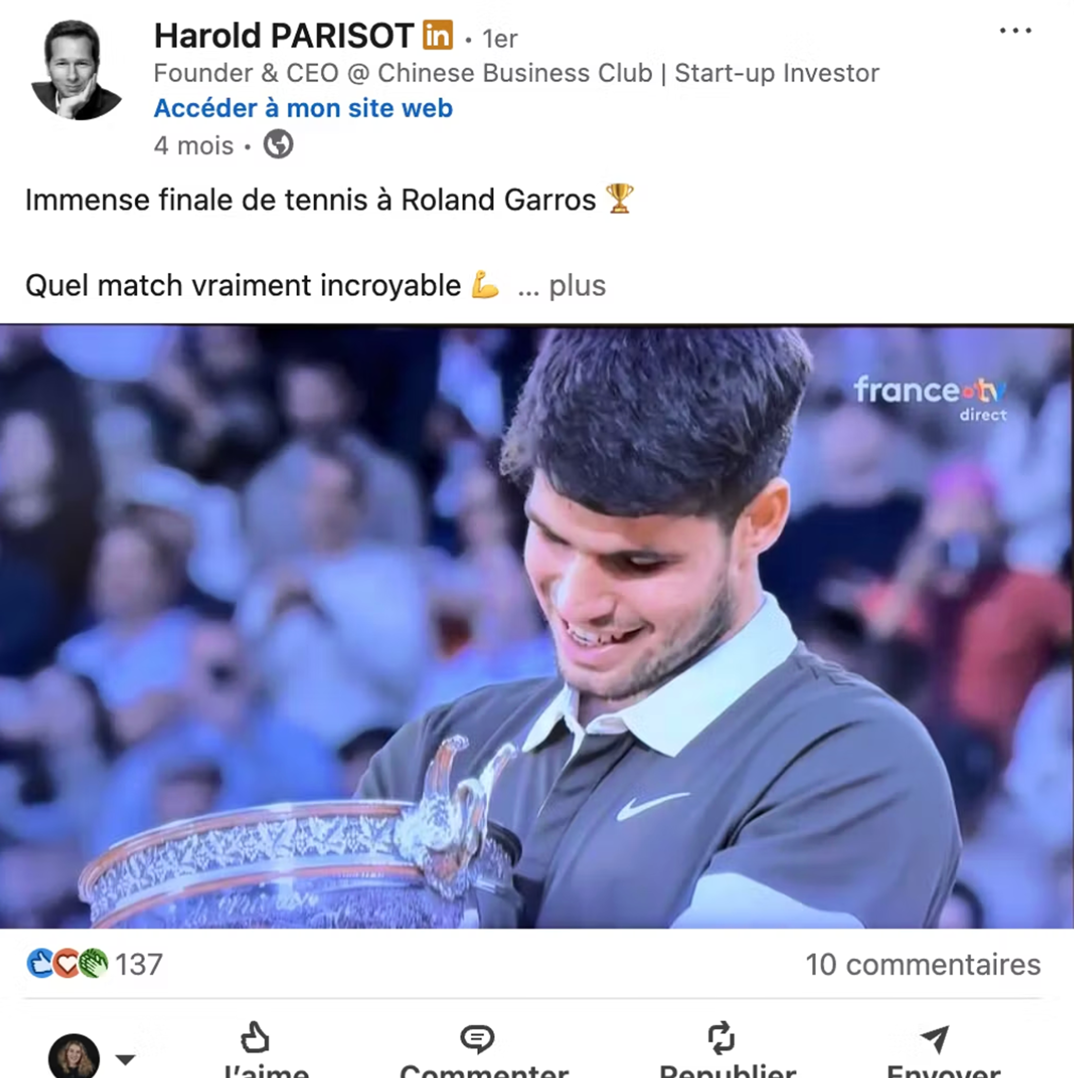 Tennis player holding and smiling at the Roland Garros trophy in a crowded stadium.