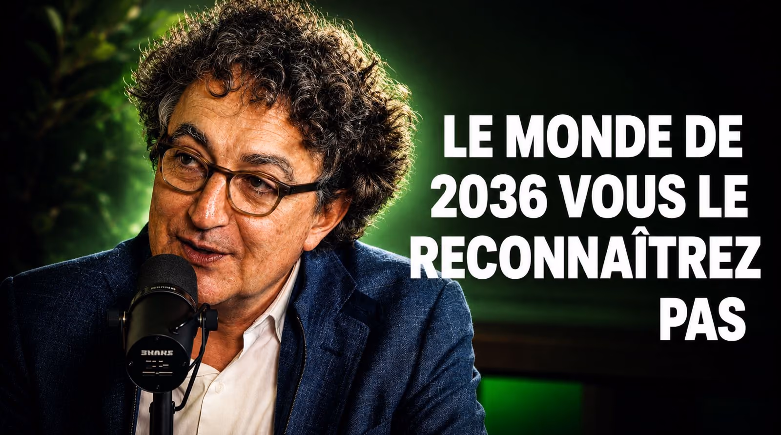 Homme aux cheveux bouclés et lunettes parlant dans un micro avec texte en français à droite.