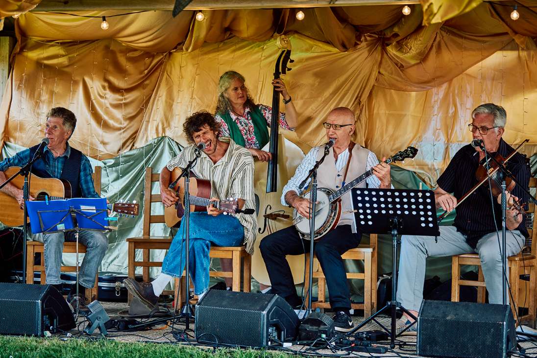 Group of people in a cozy room playing acoustic instruments and listening attentively.