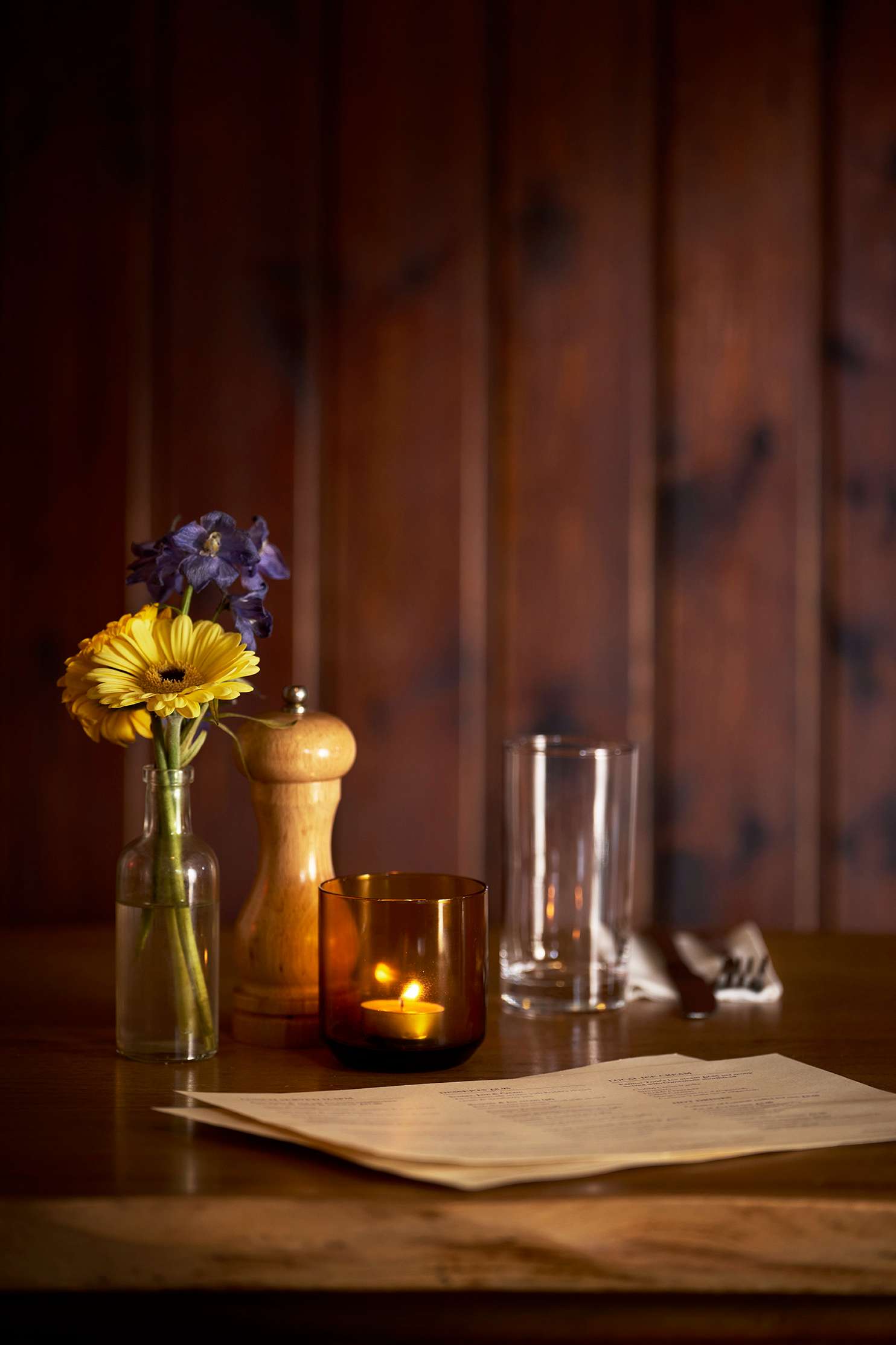 Cozy rustic dining room with wooden tables, chairs, wood stove, and exposed ceiling beams.