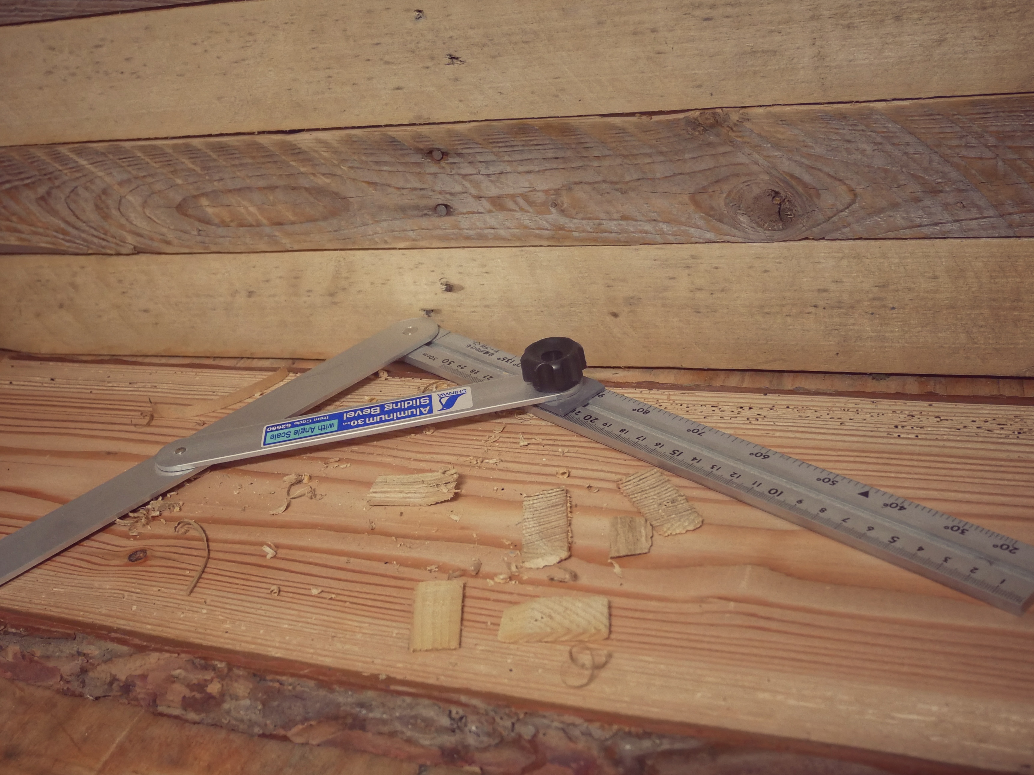 Carpenter's square aligned to measure a perfect 90-degree angle on a wooden workpiece.