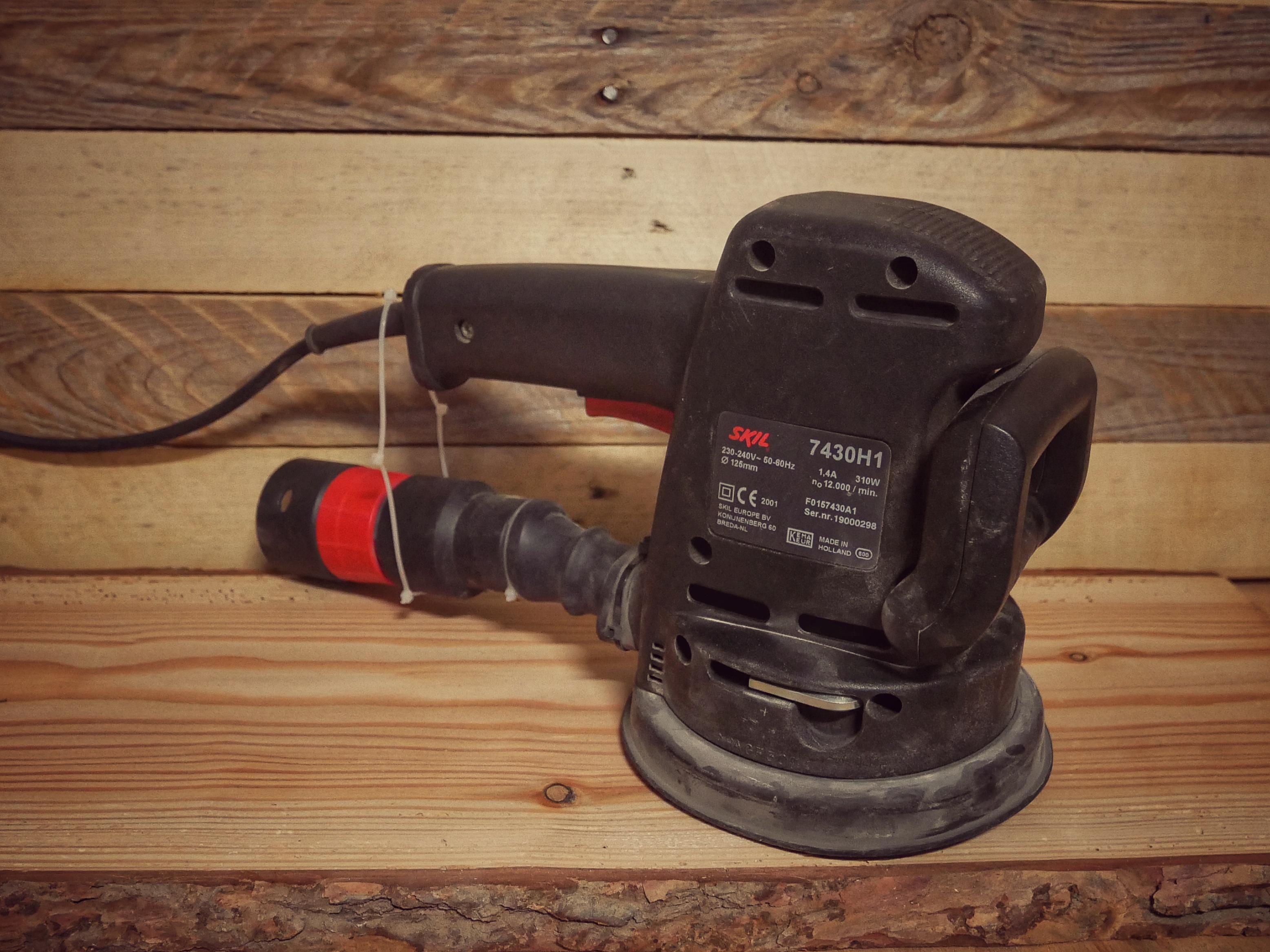 Random orbital sander smoothing a wooden surface, key for achieving professional DIY finishes.