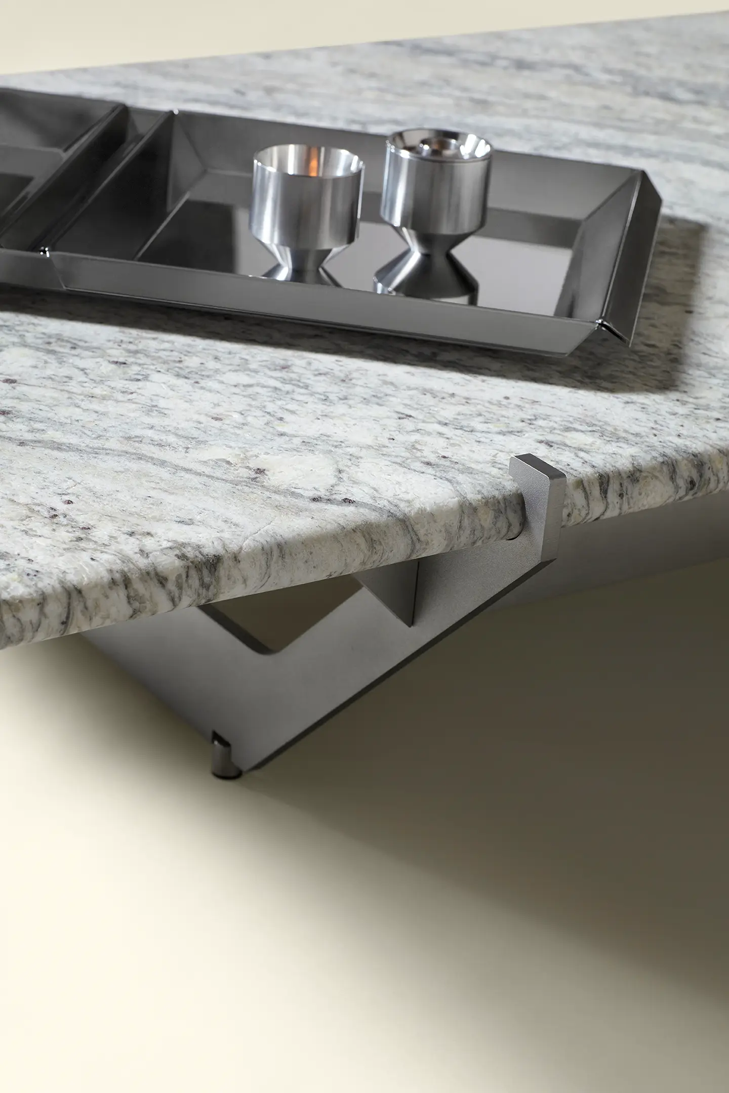 Close-up of white granite table top with metal tray and two metal candle holders on it.