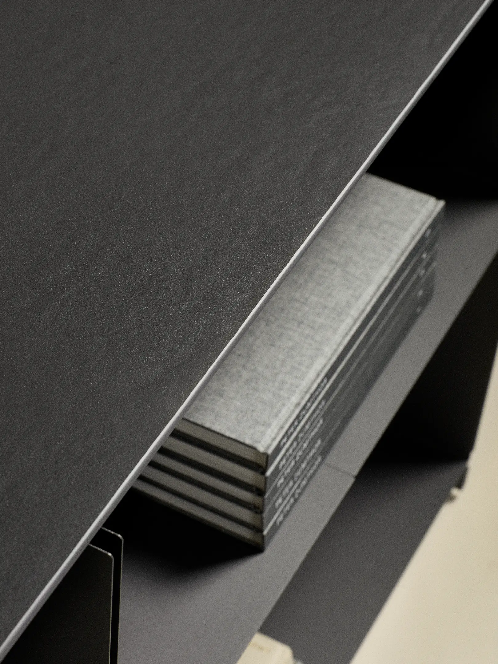 Stack of grey hardcover books placed on a dark grey shelf with a smooth top surface.