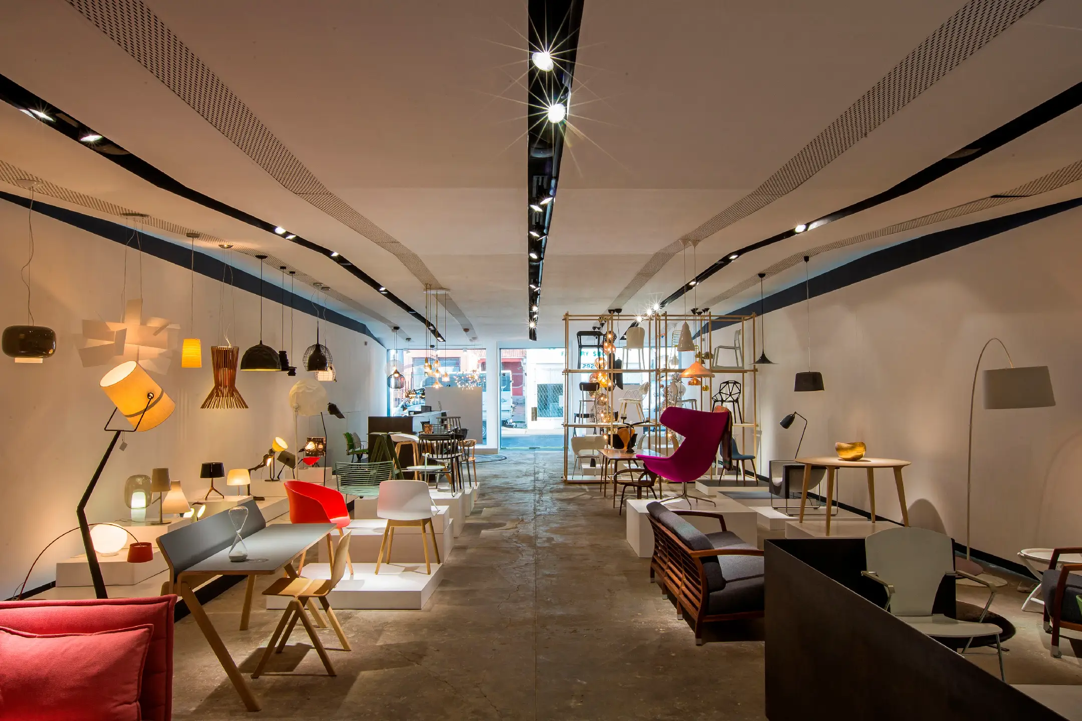 Modern furniture and various hanging lamps displayed in a spacious, well-lit showroom.