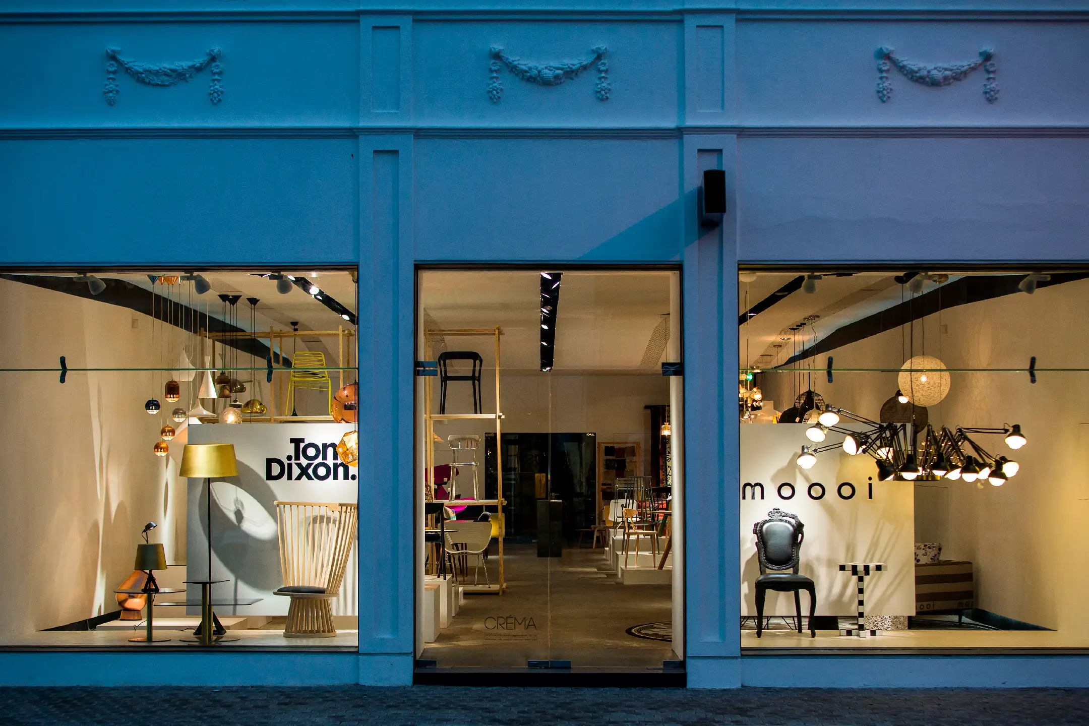 Modern furniture showroom displaying designer chairs and lighting by Tom Dixon and Moooi.