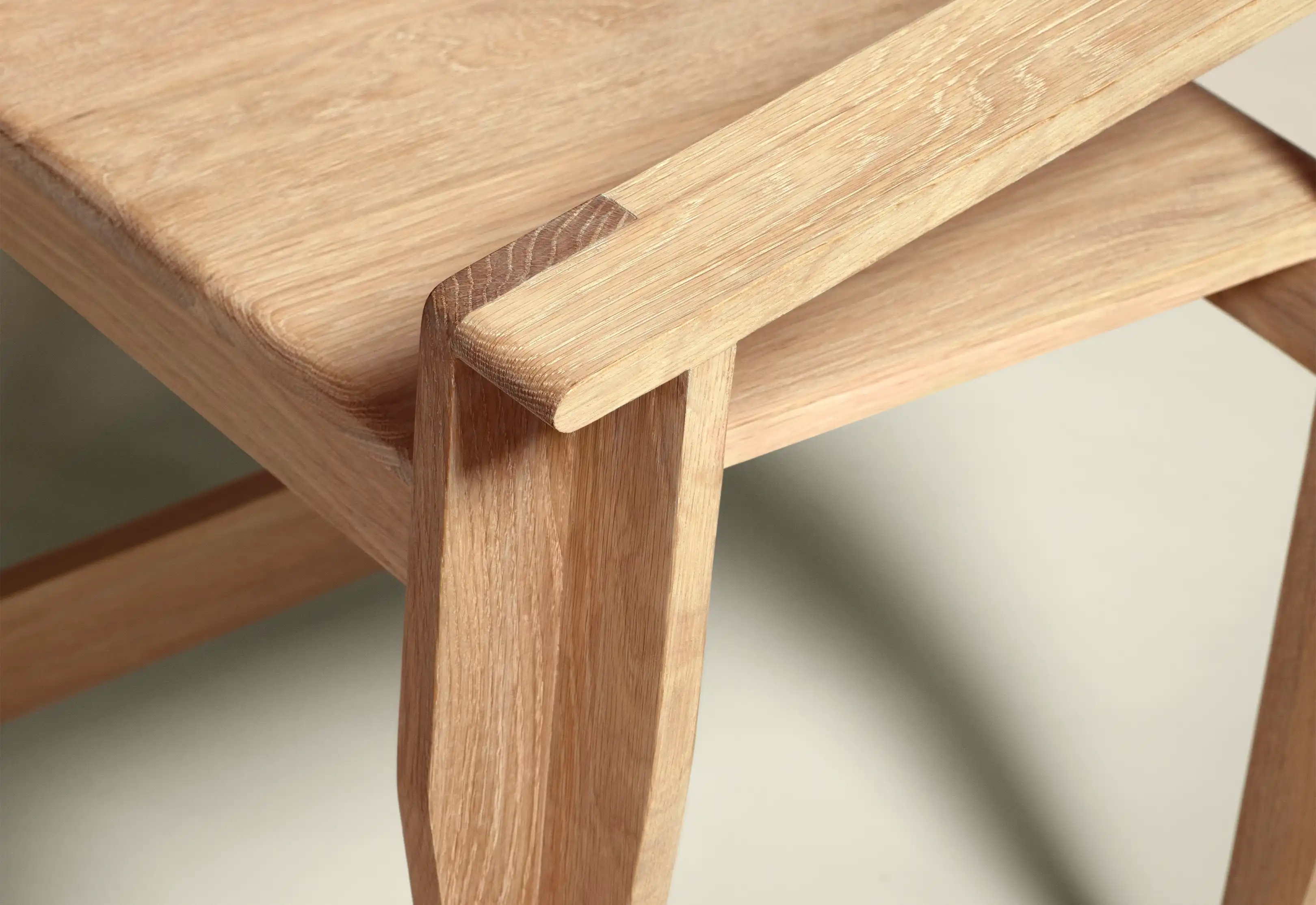 Close-up of a light wood chair leg and seat joint showing the wood grain and craftsmanship.