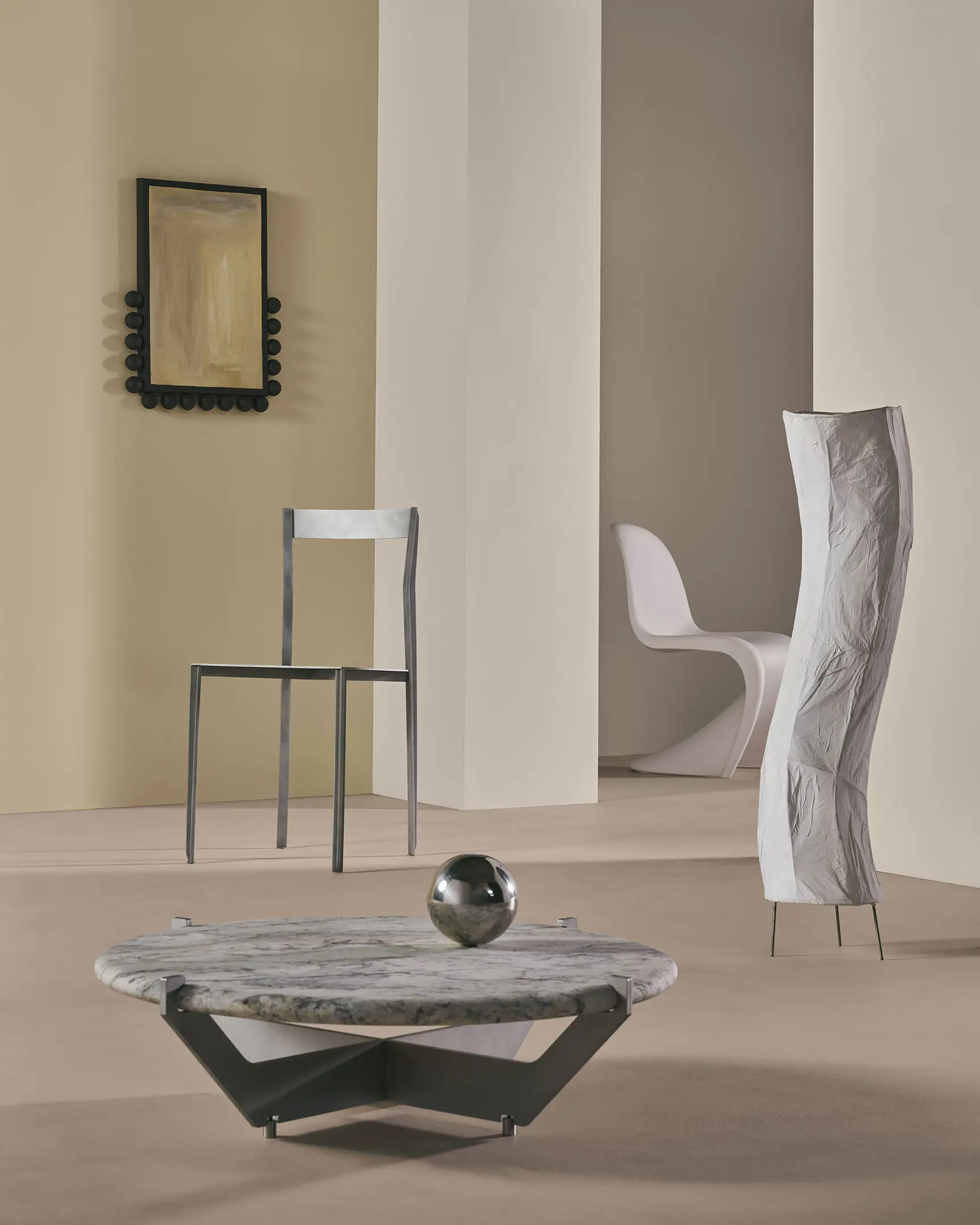 Modern interior with a marble coffee table, metal chair, sculptural lamp, and minimalist white chair.