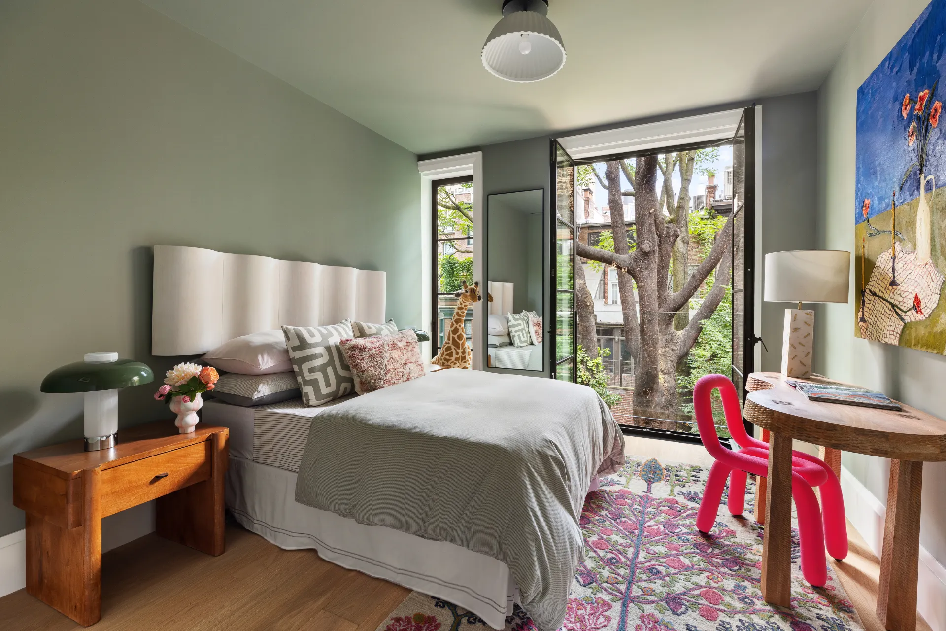 green bedroom with red chair and desk and large windows