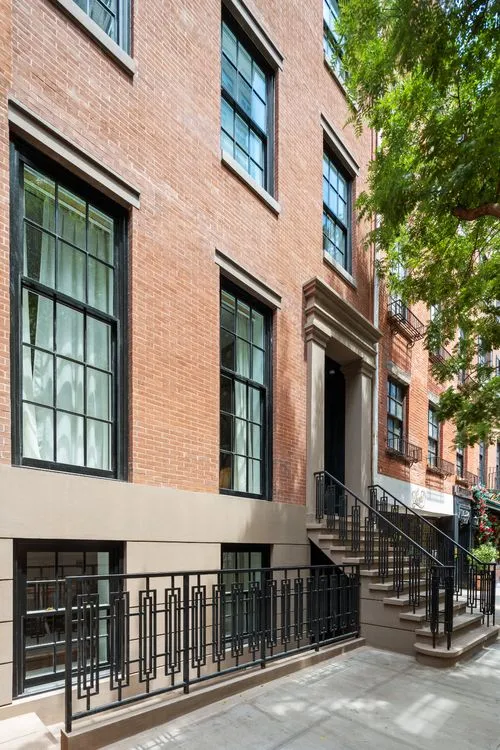 brick facade in front of residence with black iron railing and stoop