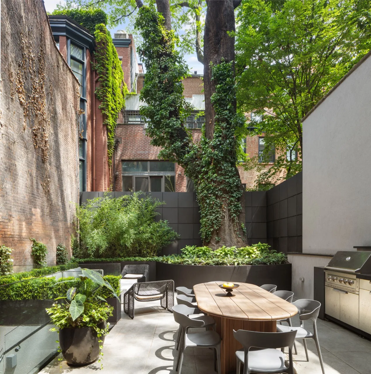 view of garden with brick wall and large tree
