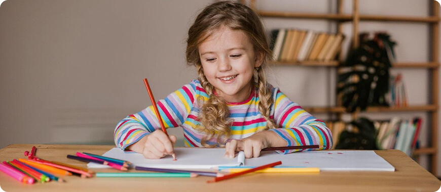 Student drawing with colored pencils while practicing Present Continuous tense — fun learning activity for kids