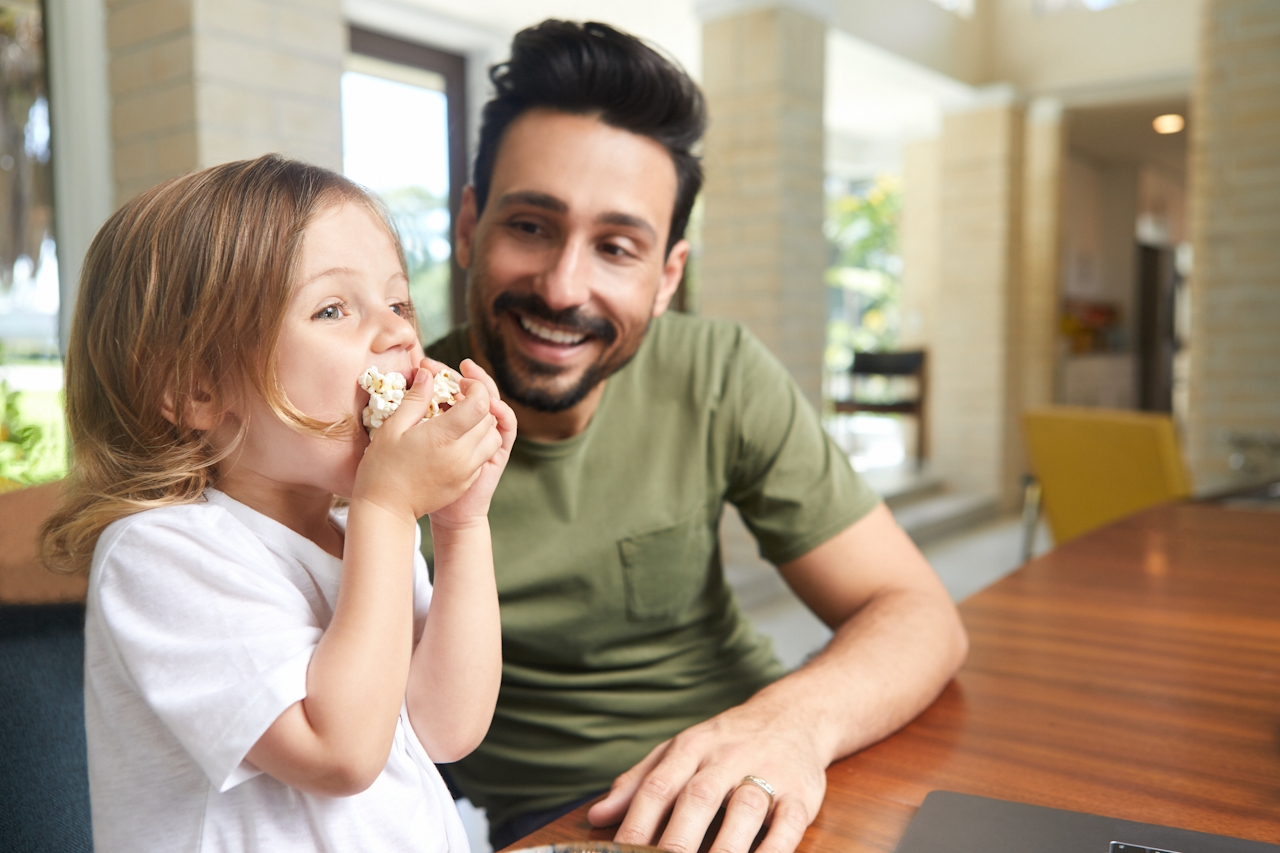 Père et enfant souriants et heureux à la maison, symbole de famille unie. Image pertinente pour le soutien en cas d'alopécie.