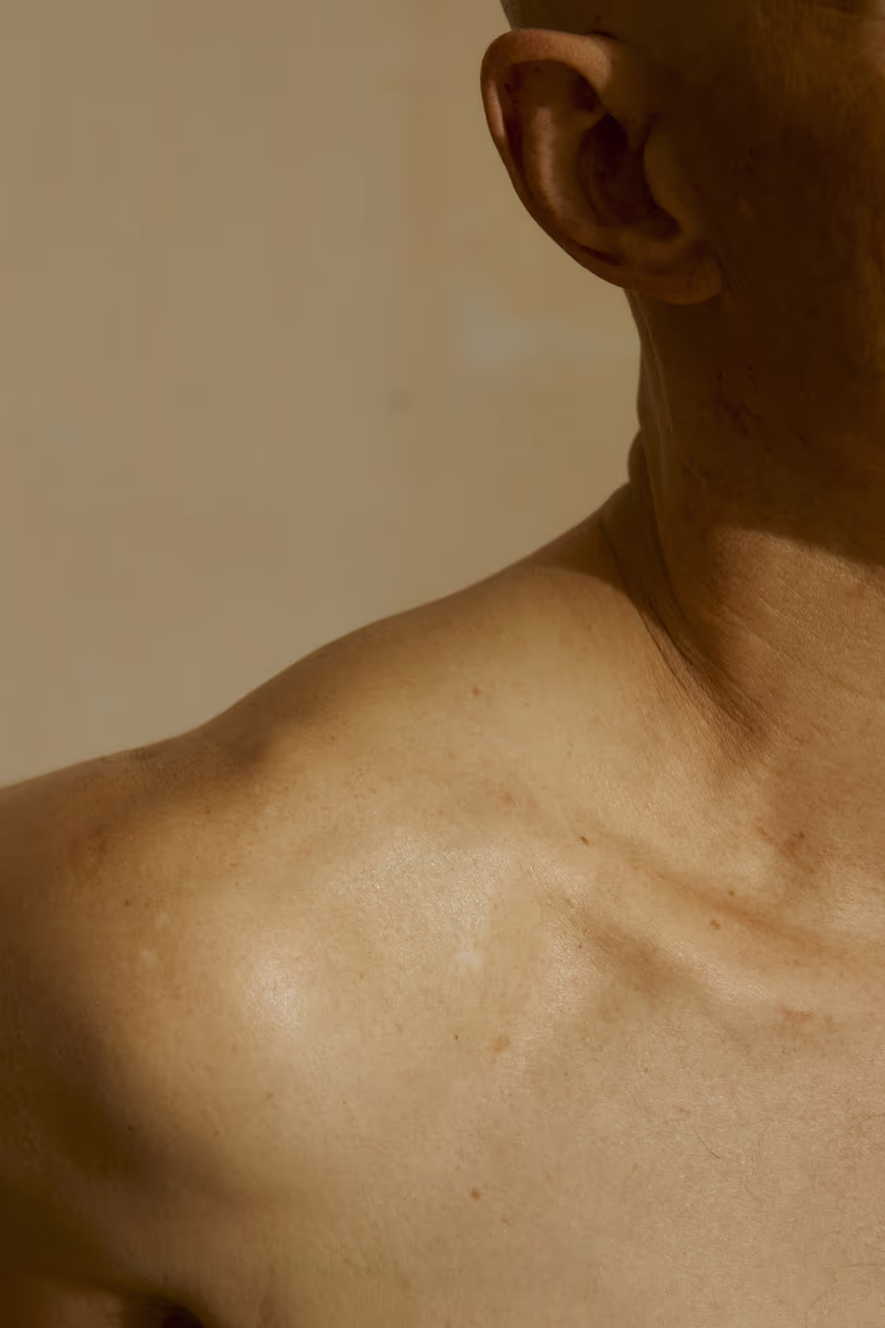 Gros plan sur l'épaule, le cou et l'oreille d'une personne, montrant la texture de la peau. Image pertinente pour le soin du corps.