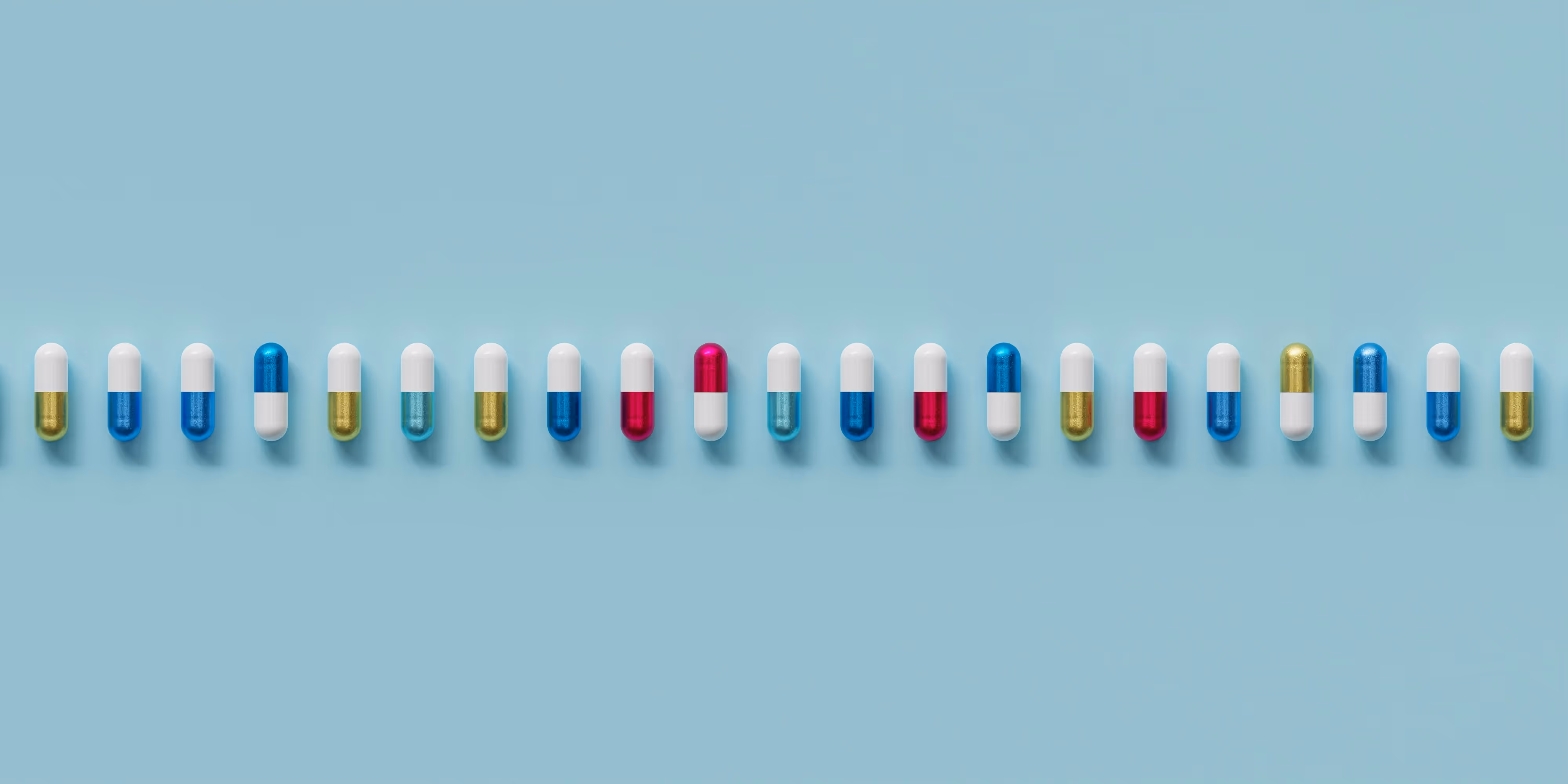 Capsules colorées alignées, symbolisant diverses options de traitement pour l'alopécie et la perte de cheveux.