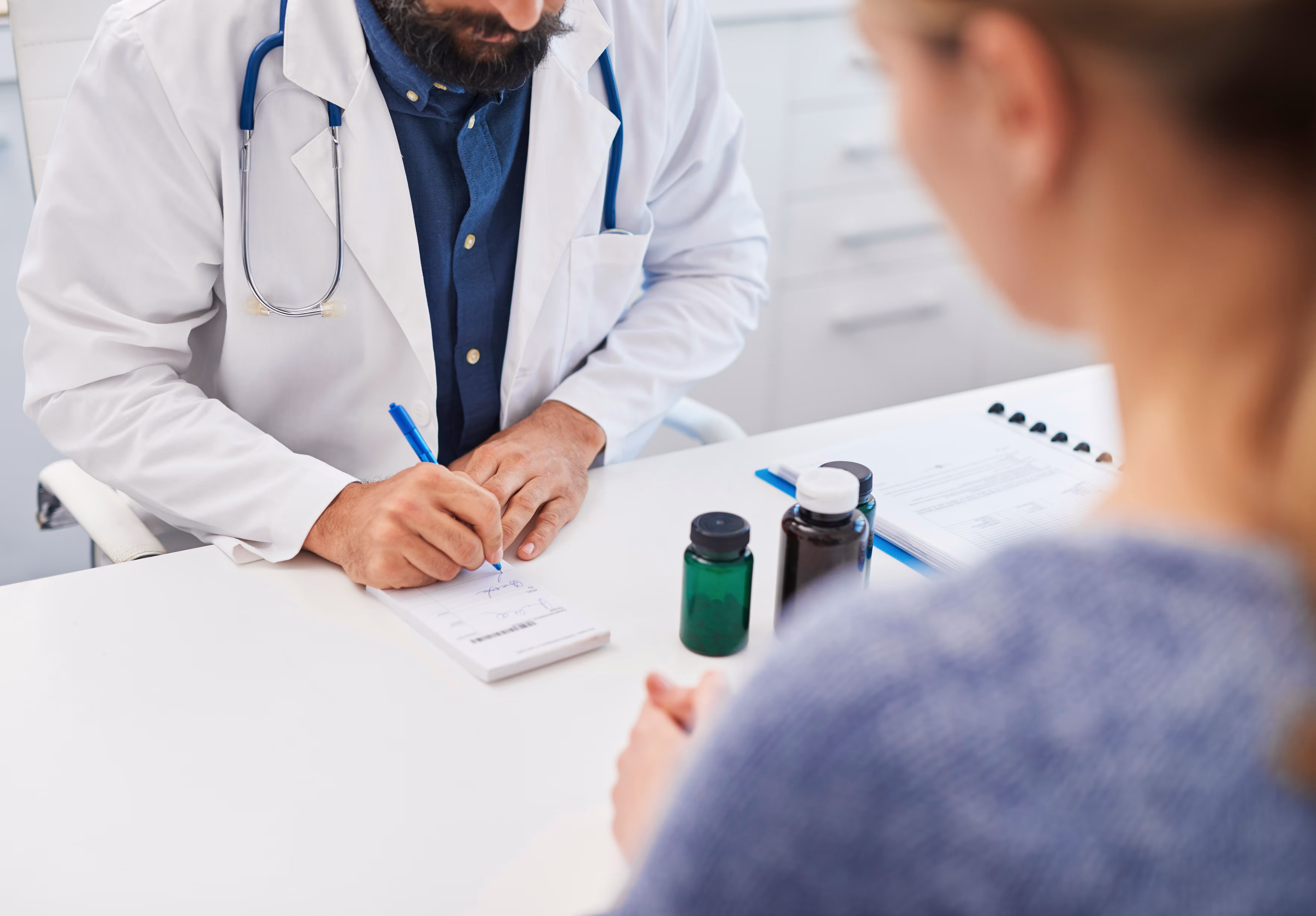 Consultation médicale pour la prise en charge de l'alopécie. Un professionnel de santé rédige une prescription, symbolisant un traitement.