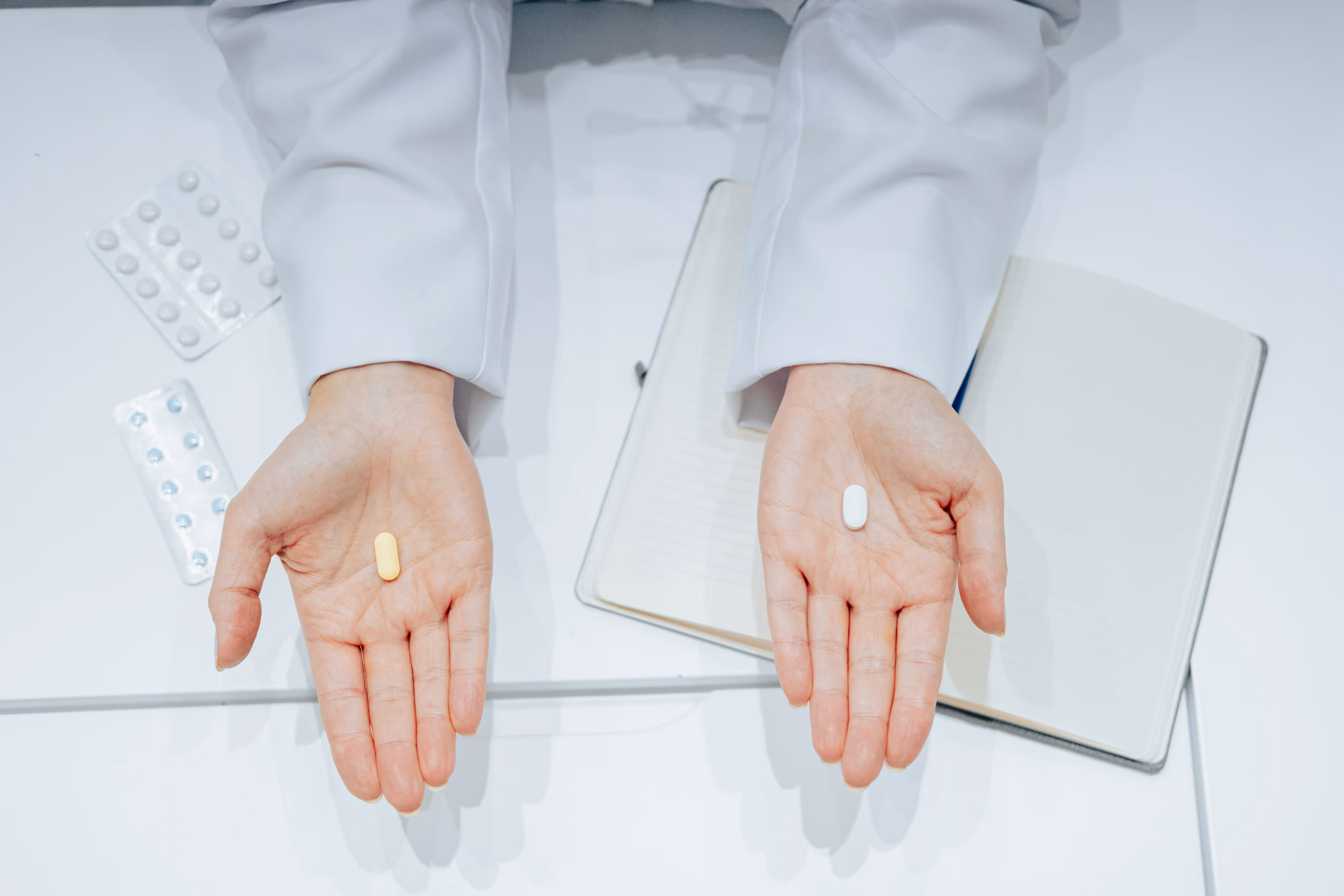 Deux mains présentent des comprimés différents, symbolisant le choix de traitements pour la gestion de l'alopécie et la santé capillaire.