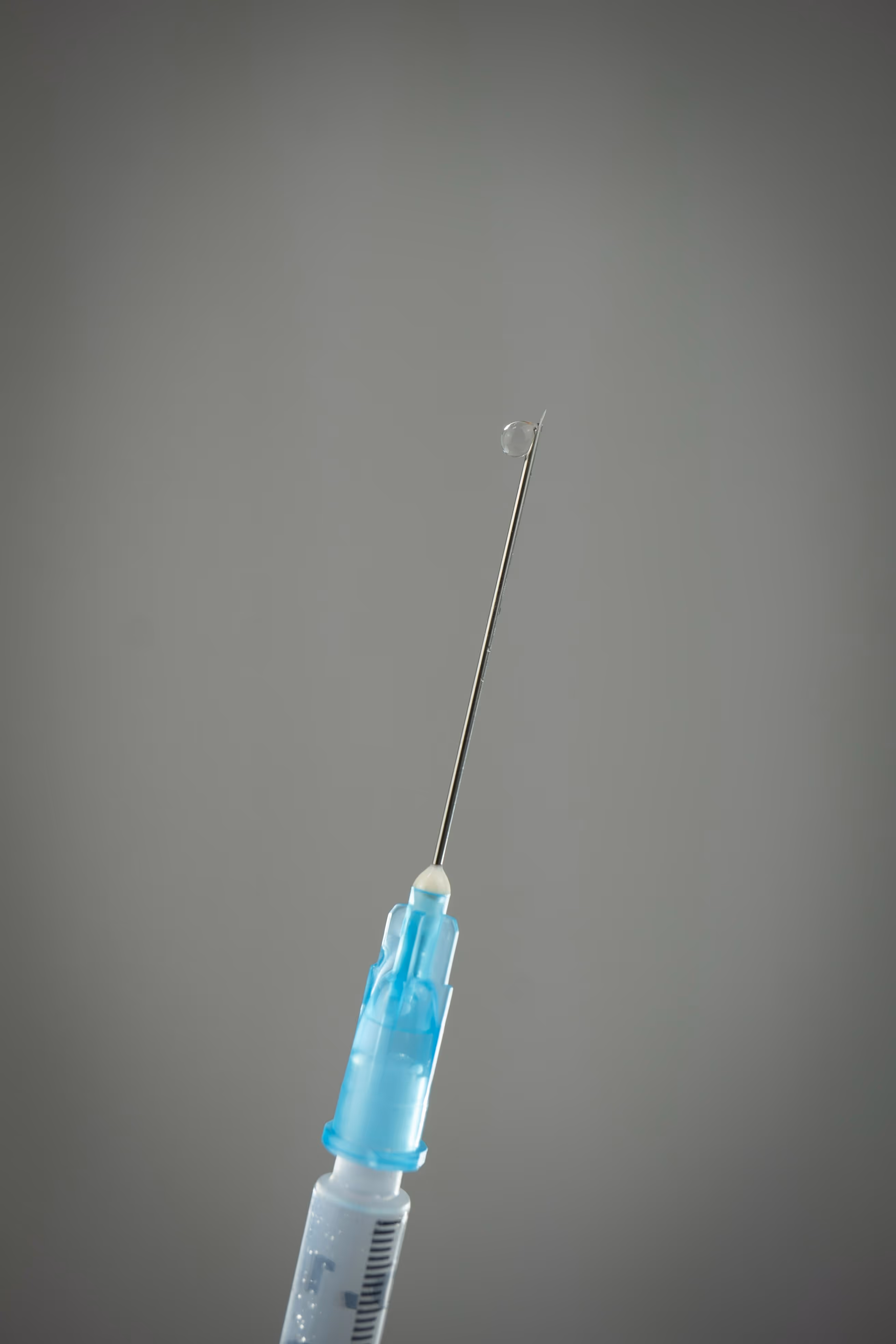 Aiguille de seringue médicale avec une goutte de liquide, illustrant un traitement pour la prise en charge de l'alopécie en France.
