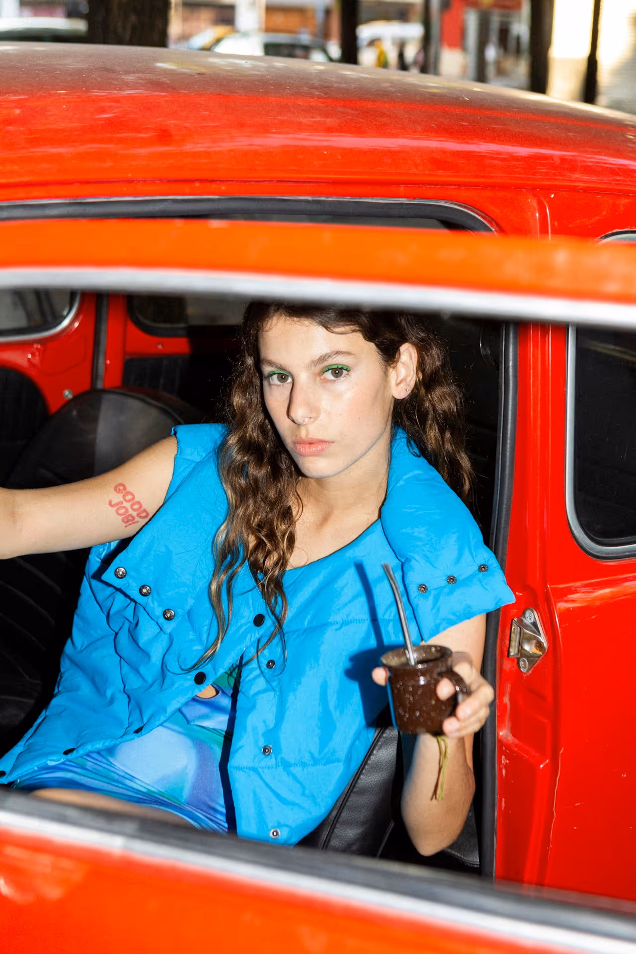 Jeune femme avec chevelure saine buvant du matcha dans une voiture rouge