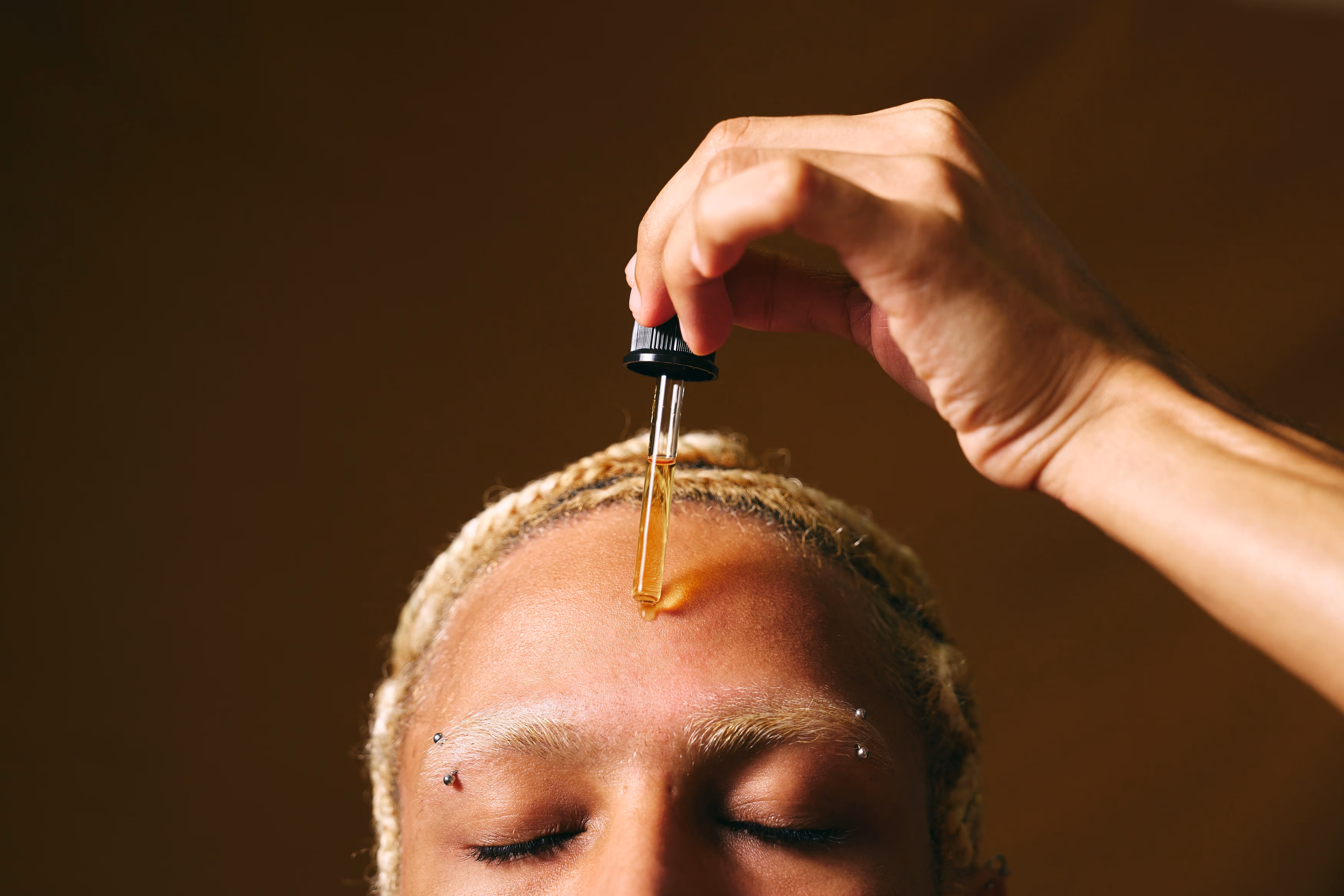 Application d'huile de soin sur la peau, routine de soin visage ou cuir chevelu.