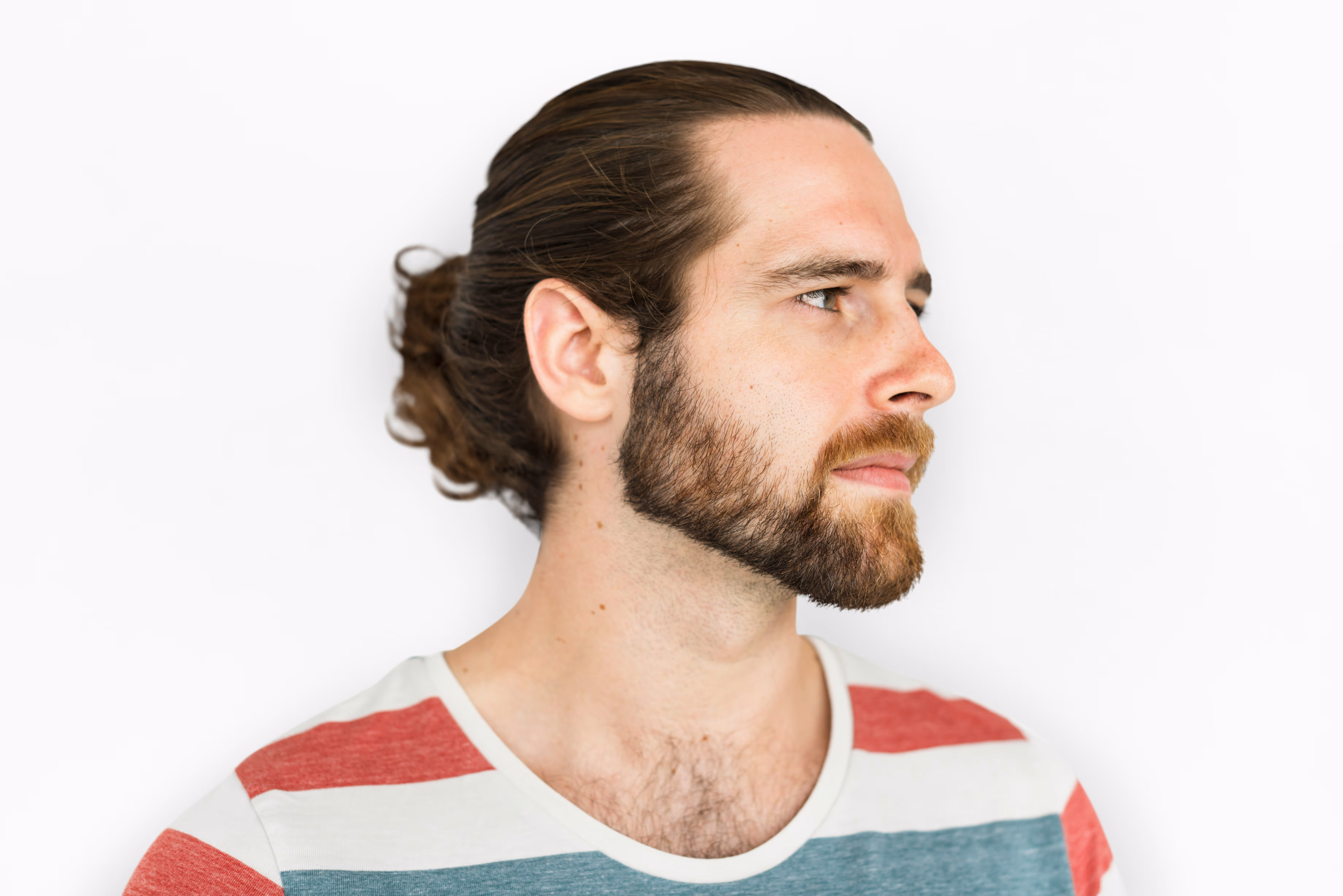 Portrait de profil d'un homme à longue chevelure brune et barbe, sur fond blanc.