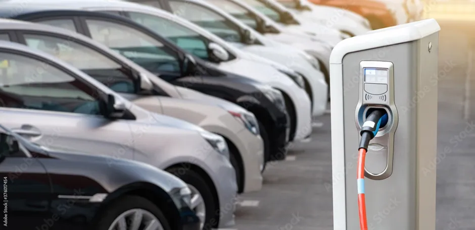 Elektrische Ladesäule mit parkenden Autos im Hintergrund 