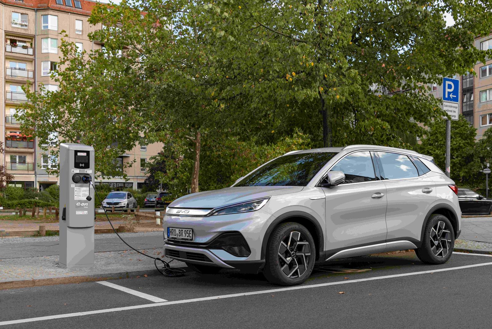 Ein grauer BYD Atto 3 steht auf einem Parkplatz und lädt an der Ladesäule.