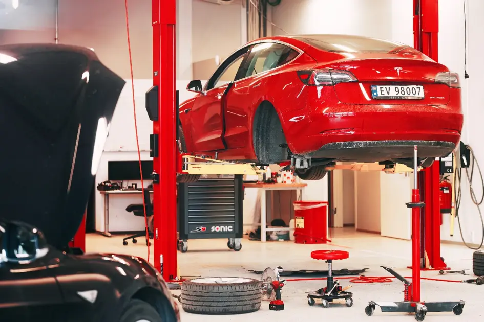 Ein rotes Tesla Model S auf der Hebebühne einer Werkstatt
