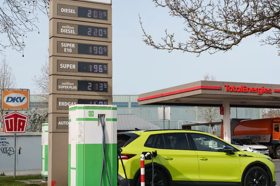 Ein Elektroauto lädt an einer Ladesäule vor der Preistafel der Tankstelle