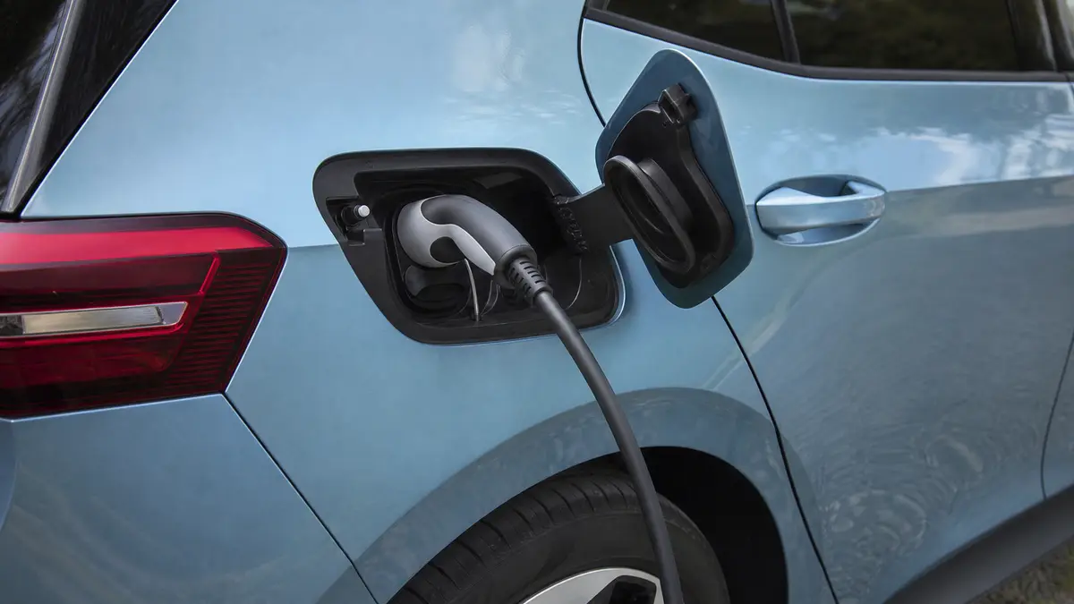Ein Typ-2-Stecker steckt in der geöffneten Ladebuchse am rechten Heck eines VW ID.3. (KI-generiert)