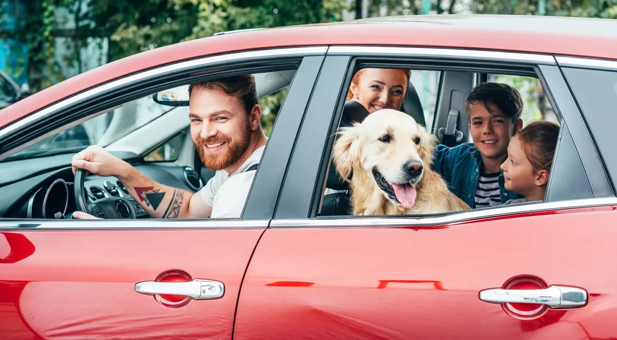 Glückliche Familie mit E-Auto und Hund
