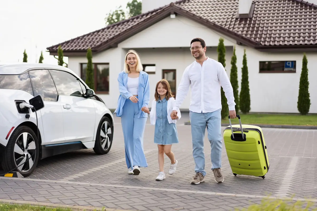 Eine Familie trifft am Ferienhaus ein während das Elektroauto schon lädt