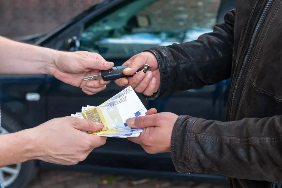 Zwei Personen übergeben sich Bargeld und einen Autoschlüssel