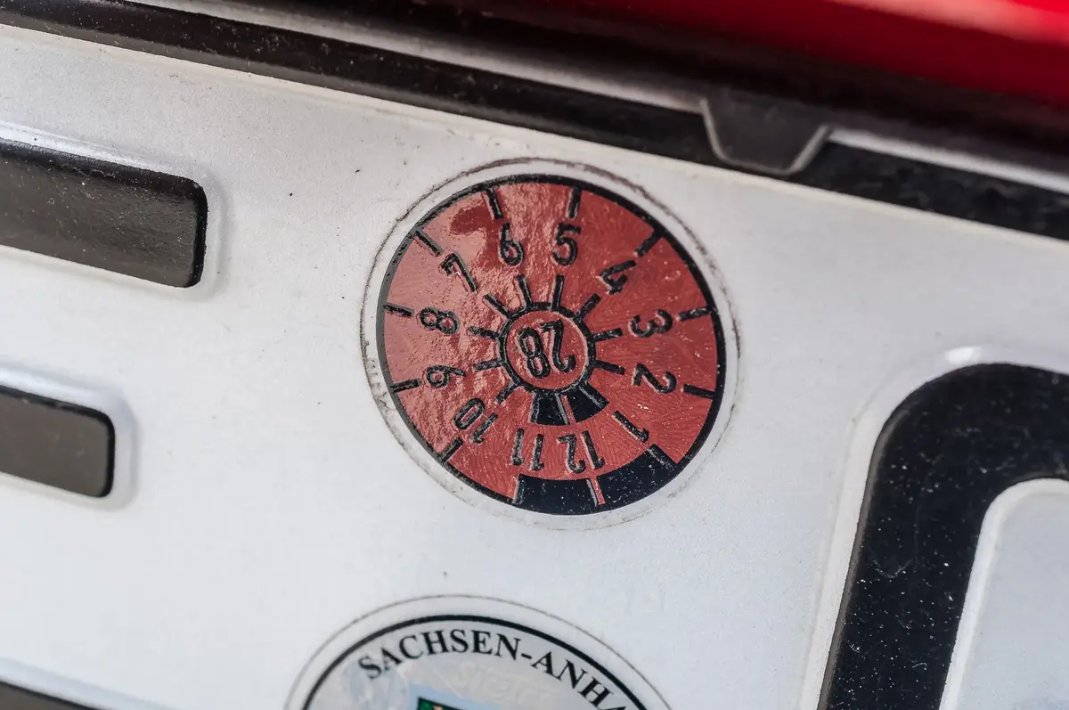 Alt-Text: TÜV-Plakette 2028 an einem Kennzeichen aus Sachsen-Anhalt
