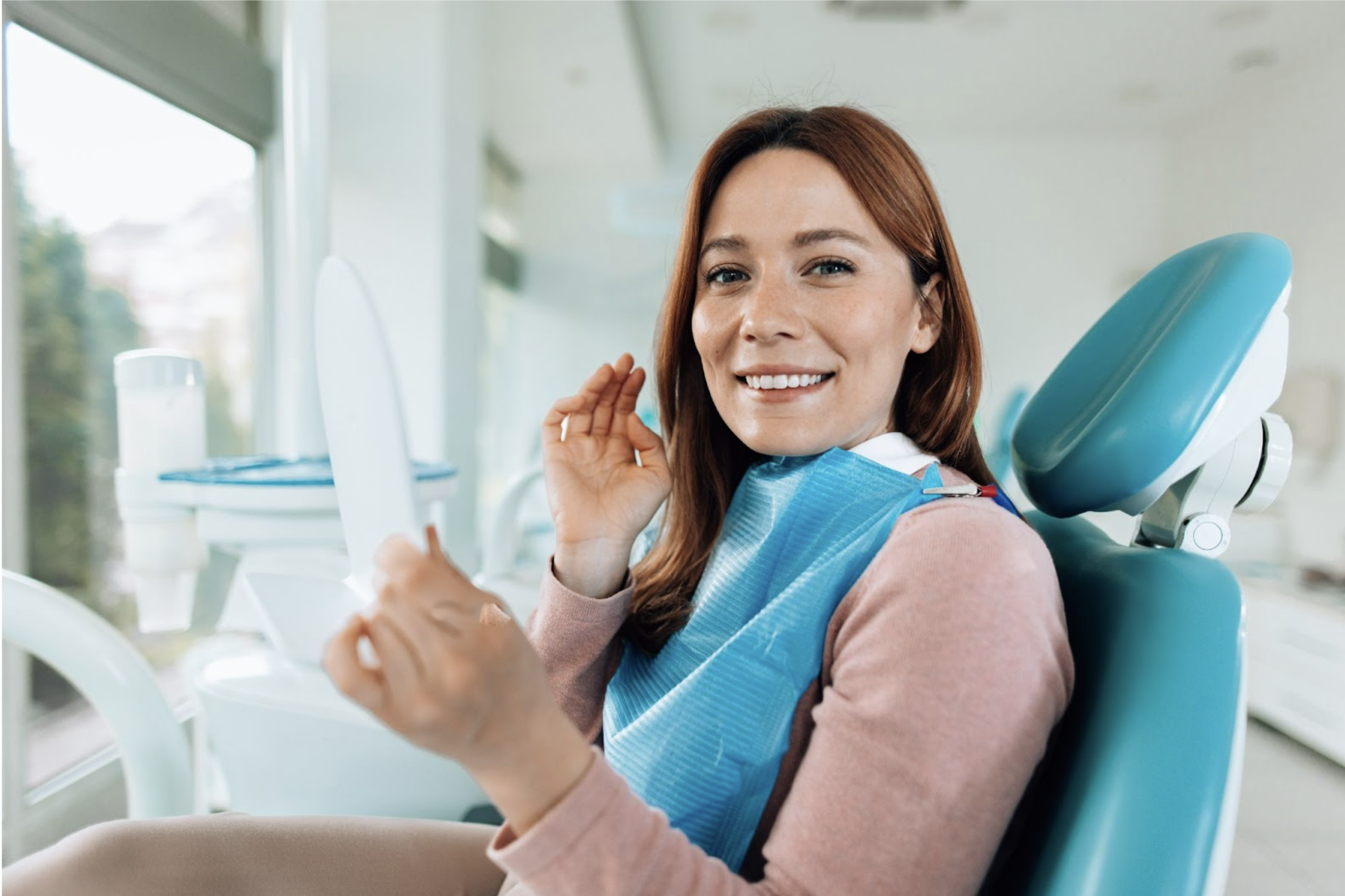 A woman receiving a dental cleaning at a dentist's office, with a dental hygienist working on her teeth.