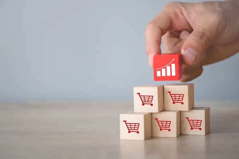 Hand arranging wood block stacking with icon Graph and shopping cart symbol upward direction