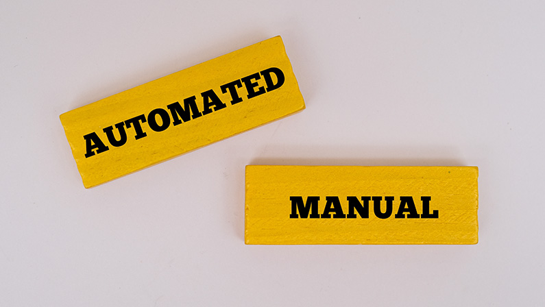 A coloured wooden block with text AUTOMATED, MANUAL. Opposites words concept