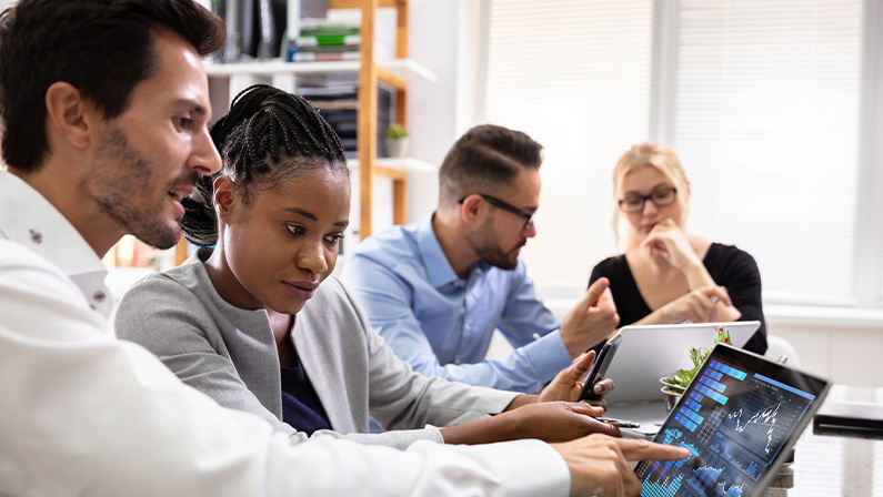 Side View Of Businesspeople Examining Graph On Computer At Workplace