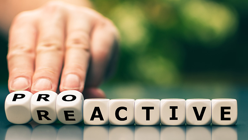 Hand turns dice and changes the word reactive to proactive.