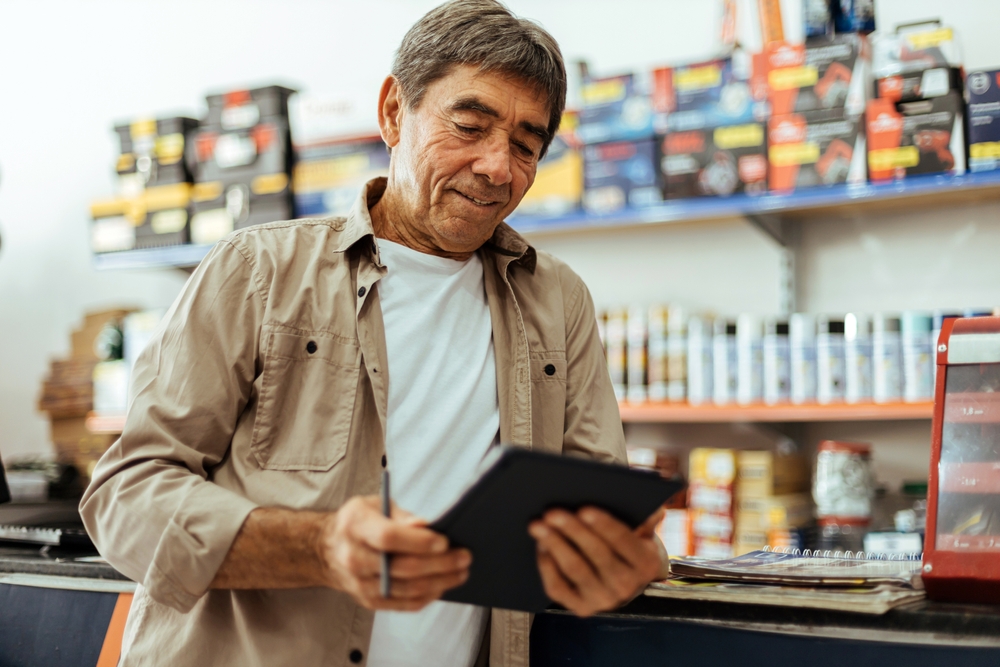 Elderly man working in a hardware store using digital tablet. Small business concept.