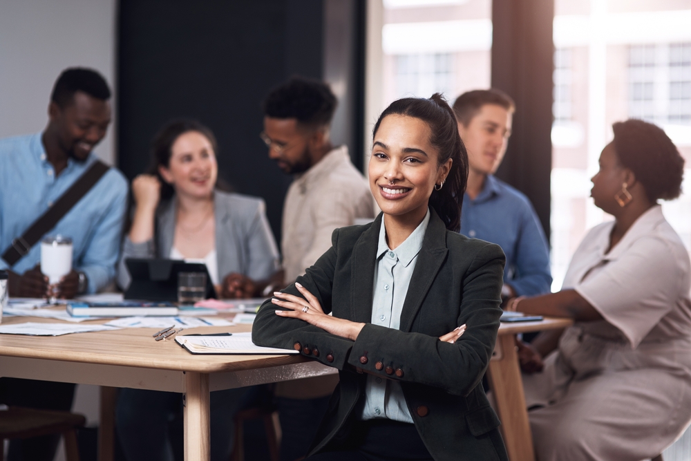 Portrait, smile and business woman with arms crossed at meeting with team for job pride or coworking.