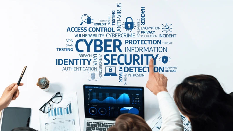 A detailed view of a cybersecurity session with a team analyzing data on a laptop, highlighting important concepts like protection, detection, and vulnerabilities in a professional setting. Amity