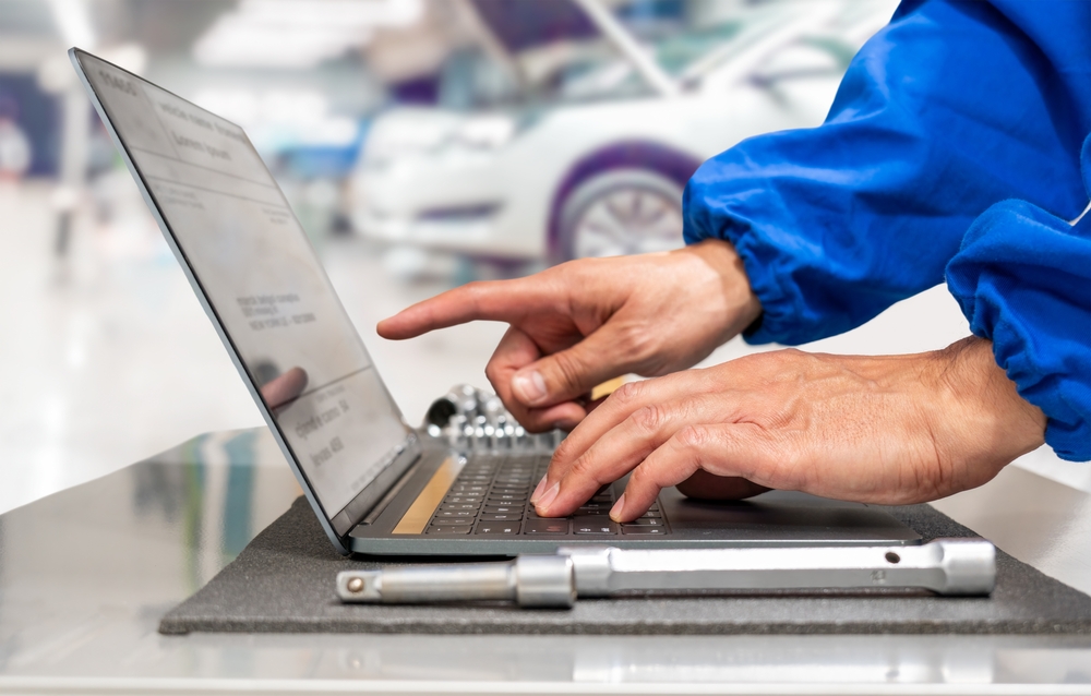 Close-up of hands of manager at the auto repair shop using a laptop