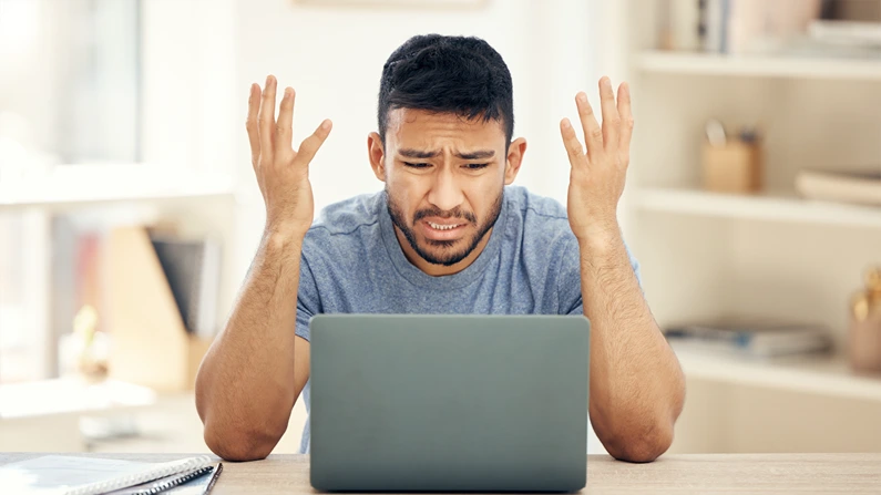 A man looking at his laptop with angry reaction