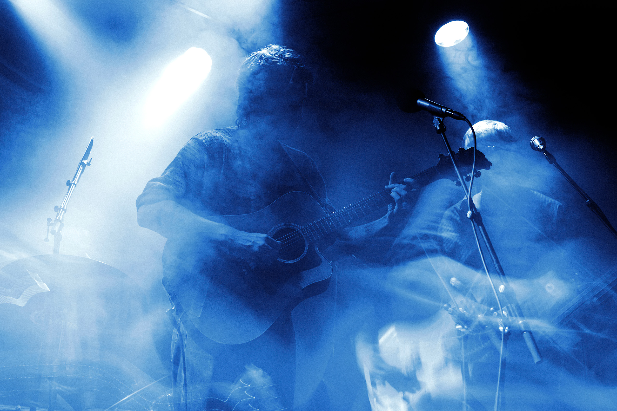 Thoughtfool performing with acoustic guitar at Rust in Copenhagen surrounded by blue stage lights and smoke.