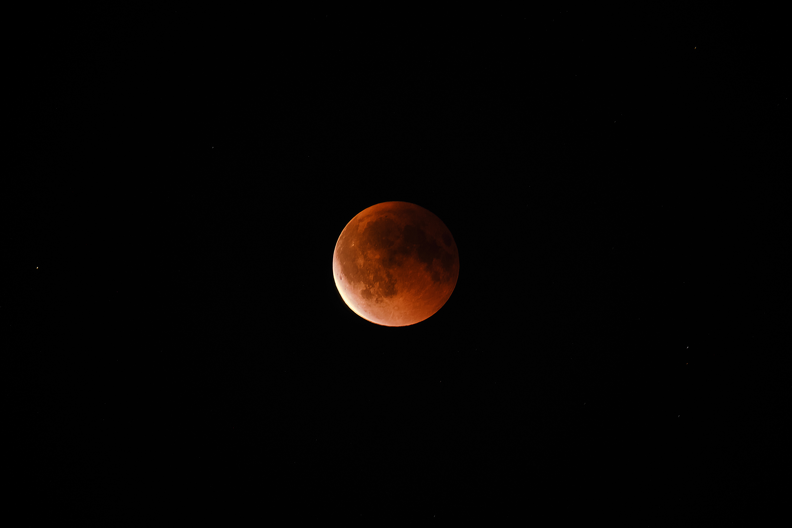 Astrophotography of a blood moon during a total lunar eclipse against a dark night sky.