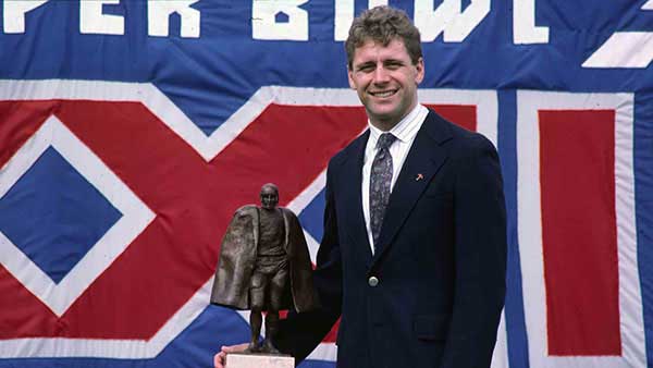 Steve Largent posing in front of the Walter Payton man of the year award